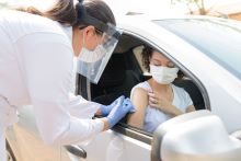 Nurse performs vaccination at car