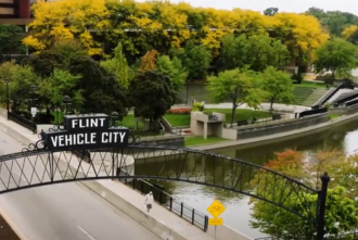 Flint Vehicle City street sign over Flint River