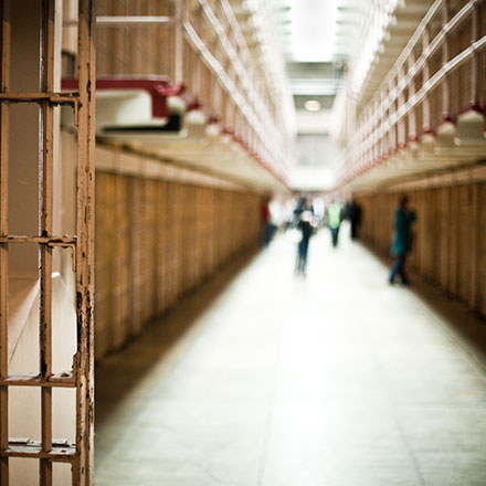 Inside of a jail corridor with a few people standing in the distance