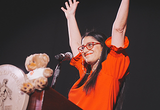 Dr Mona in red with arm in the air being interviewed