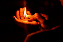 Hands holding a lit match and shining a light